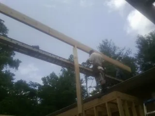 Carpenter setting a ridge beam over a new addition frame — Ice Dam Removal by Roofing Brothers in West Townsend