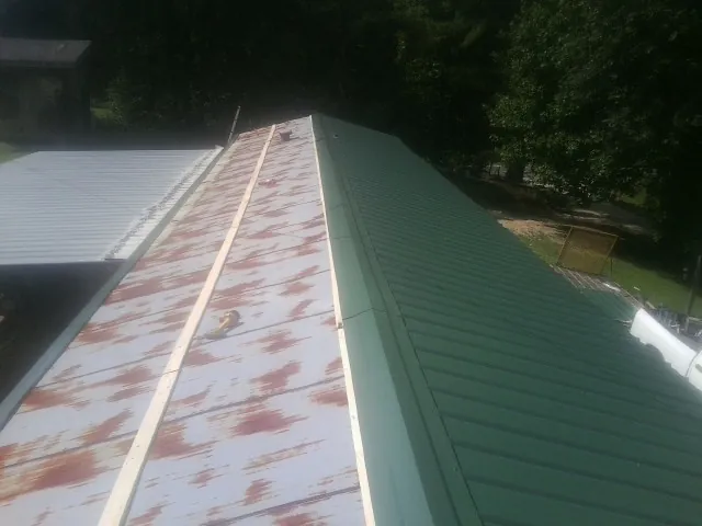 Old rusted panels beside newly installed green metal roofing — Wind Damage Roof Repair by Roofing Brothers in West Townsend