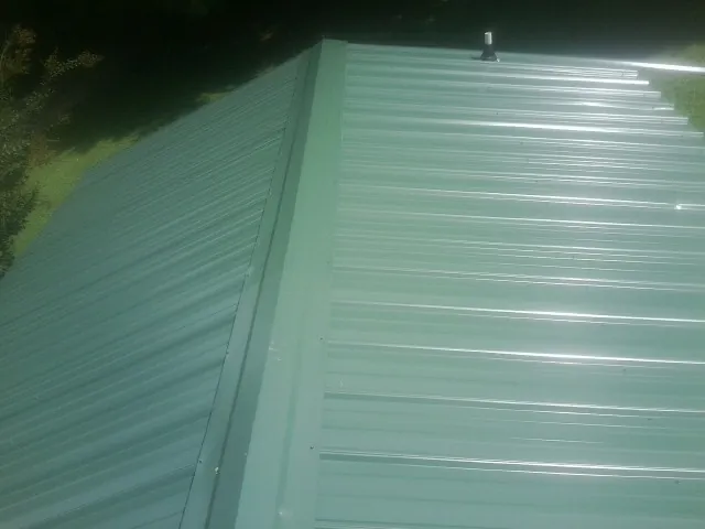 New green metal panels meeting at the ridge of a roof — Flat Roof Repair work by our crew in West Townsend