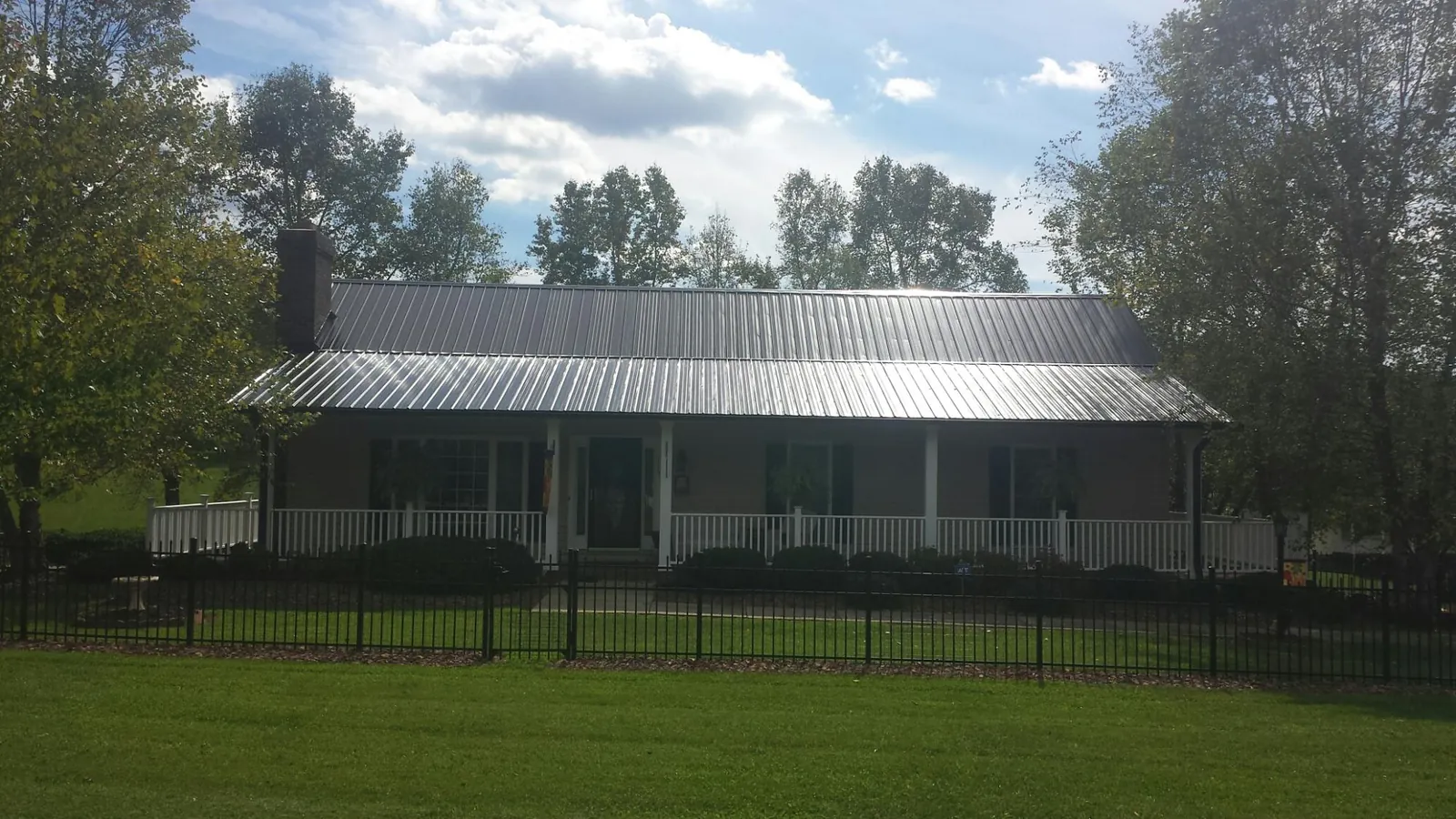 Gray metal roof on a brick ranch with a full width front porch — Gutter Guard Installation work by our crew in West Townsend