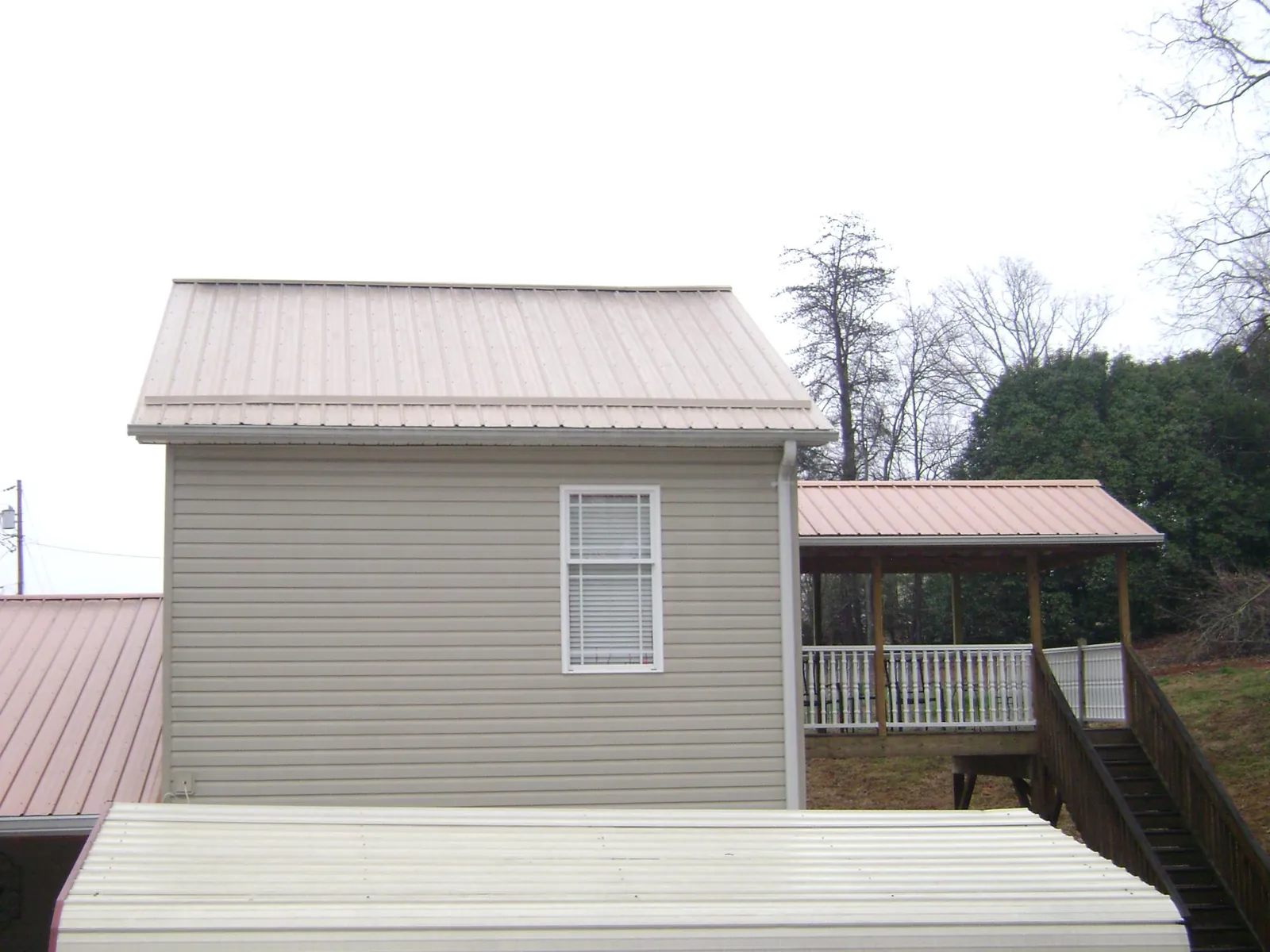 Tan metal roofs on a two story addition and attached porch, from a Roof Replacement job in West Townsend