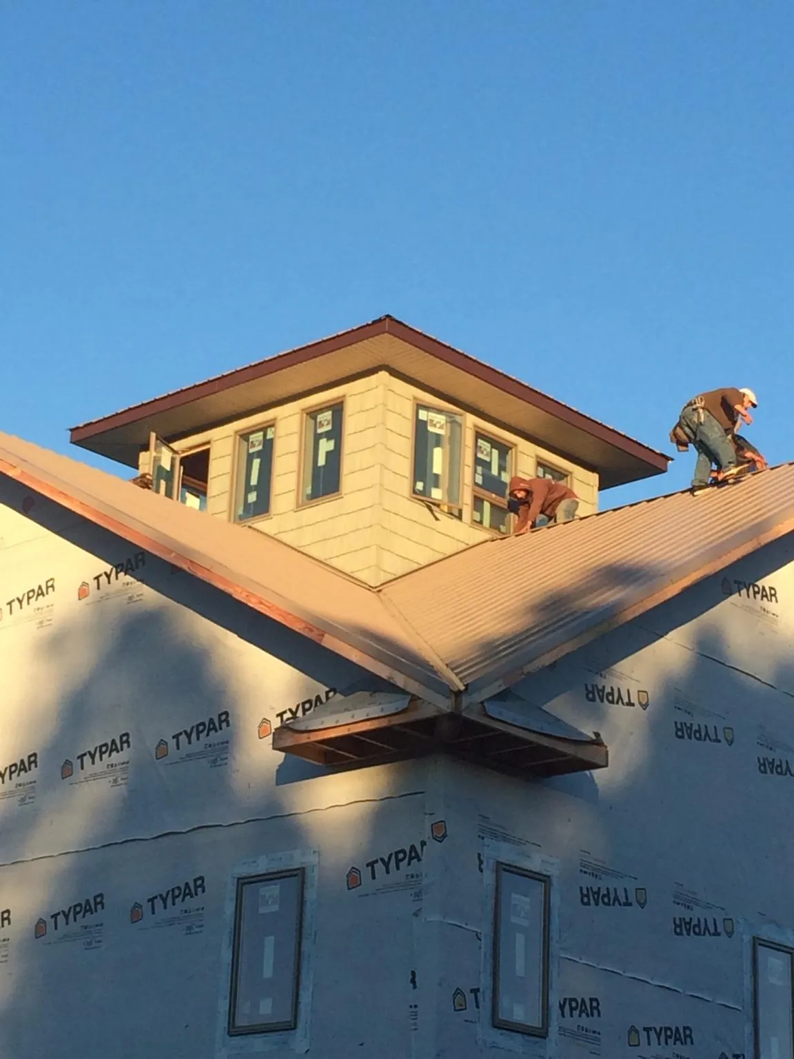 Roofers working around a rooftop cupola on a new metal roof at sunset — Roof Waterproofing in West Townsend by Roofing Brothers